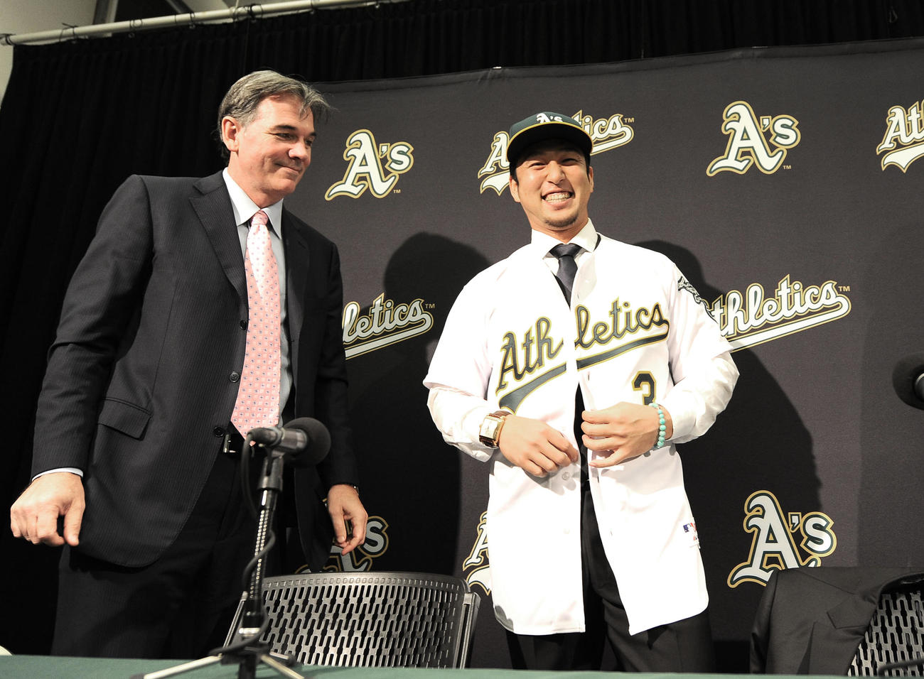 アスレチックス入団会見で背番号3のユニホームに袖を通し、笑顔を見せる中島。左はビリー・ビーンGM（2012年12月撮影）
