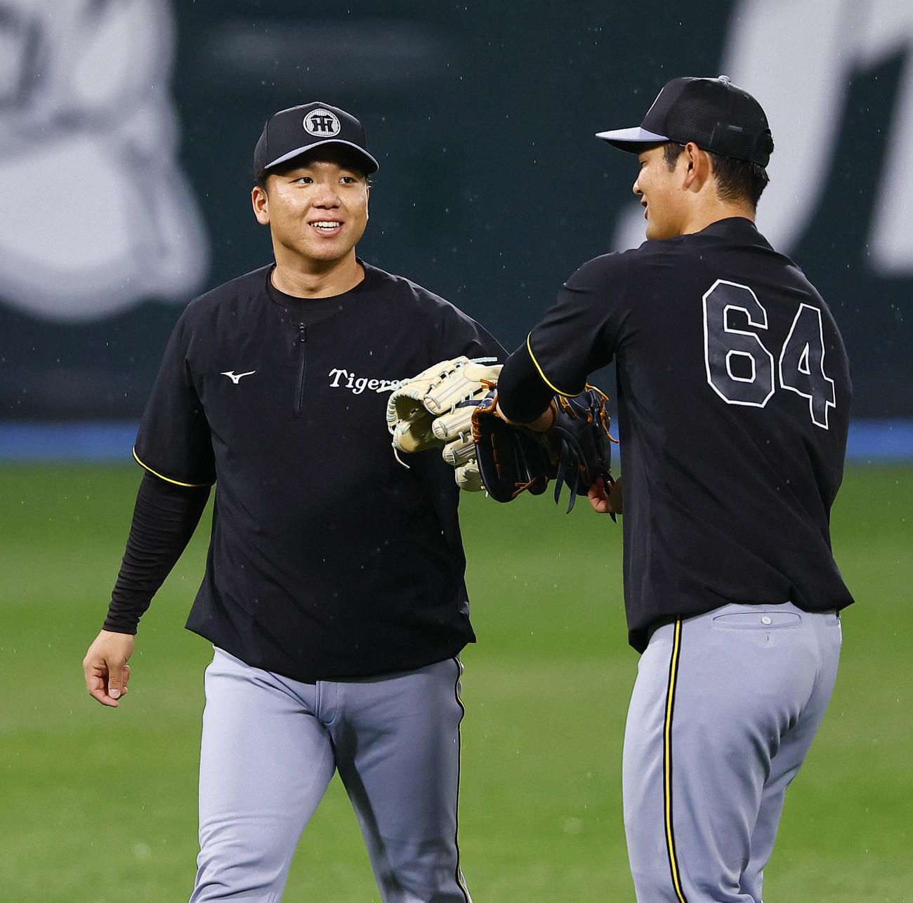 キャッチボールを終え、岡留と笑顔でタッチを交わす阪神村上（撮影・藤尾明華）