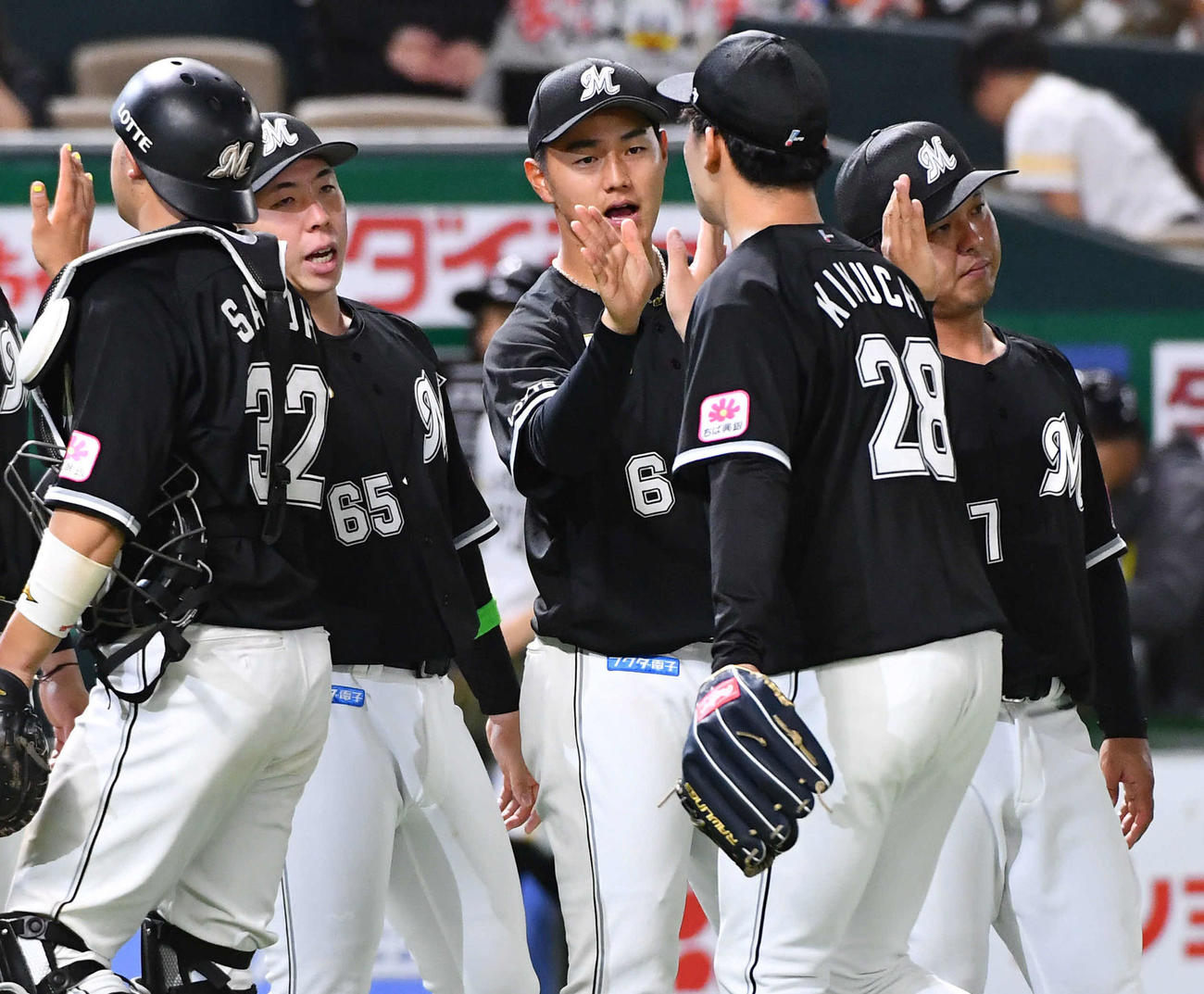 ソフトバンク対ロッテ　開幕戦でソフトバンクに勝利し、最終回を抑えた菊地（右から2人目）らナインとハイタッチするロッテ西川（撮影・岩下翔太）
