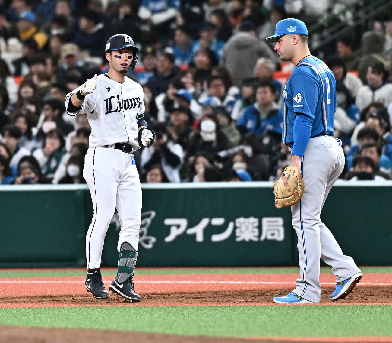 西武対日本ハム　6回裏西武2死一、三塁、外崎（左）は中前適時打を放ちサムズアップする。一塁手マルティネス（撮影・滝沢徹郎）