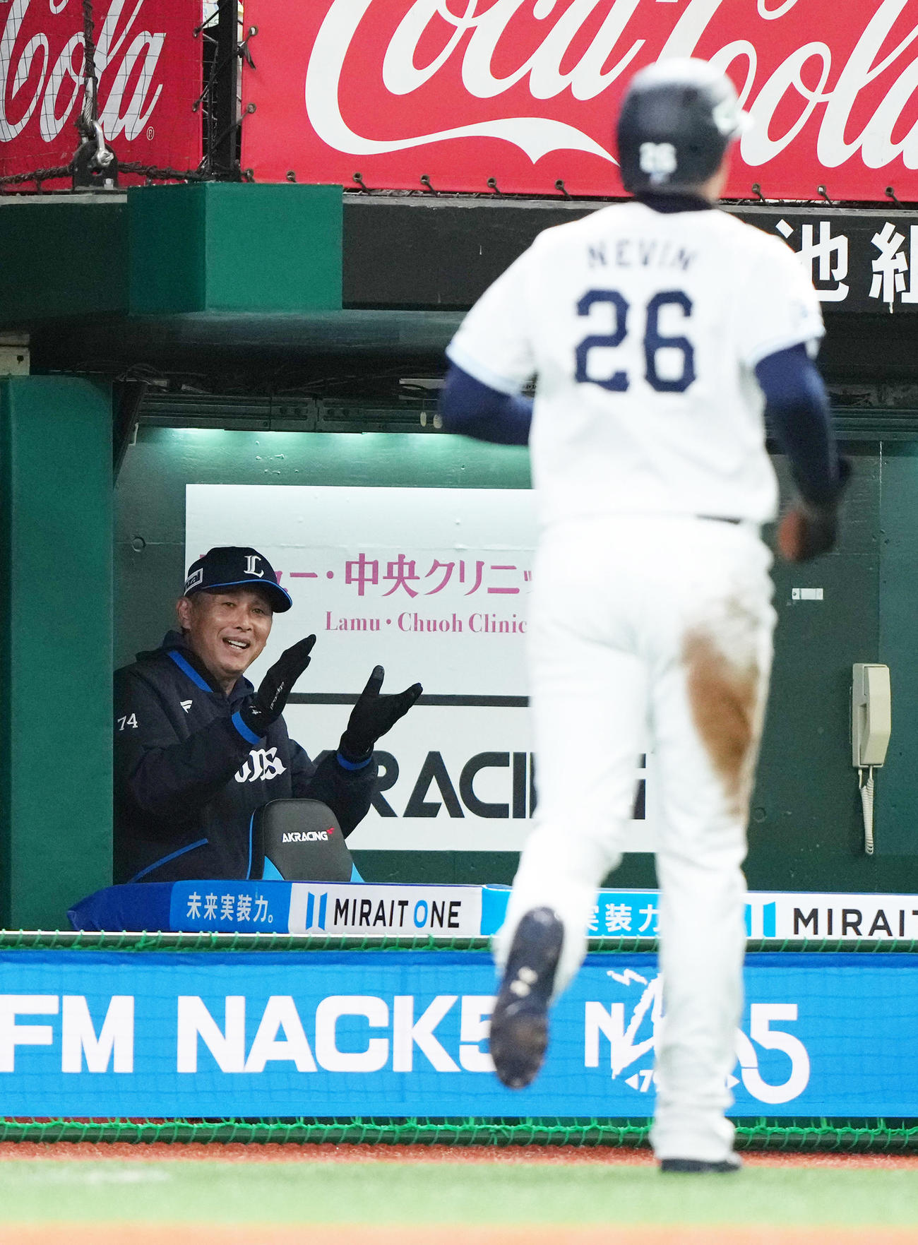 西武対日本ハム　6回裏西武2死一、三塁、外崎の中前適時打で生還したネビン（右）を拍手で迎える西口監督（撮影・足立雅史）