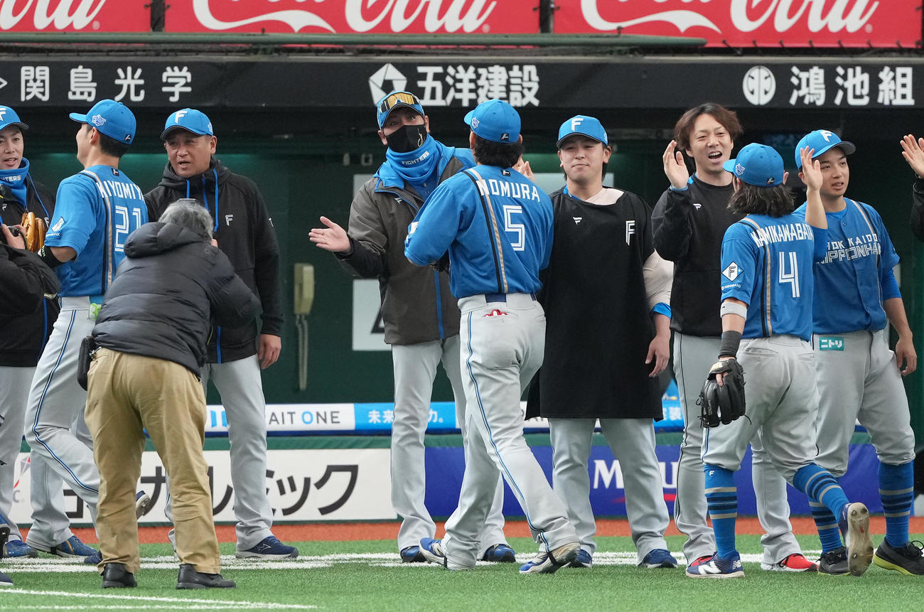 西武対日本ハム　開幕3連勝を飾った日本ハム新庄監督（中央左）は野村（同右）らをタッチで迎える（撮影・足立雅史）