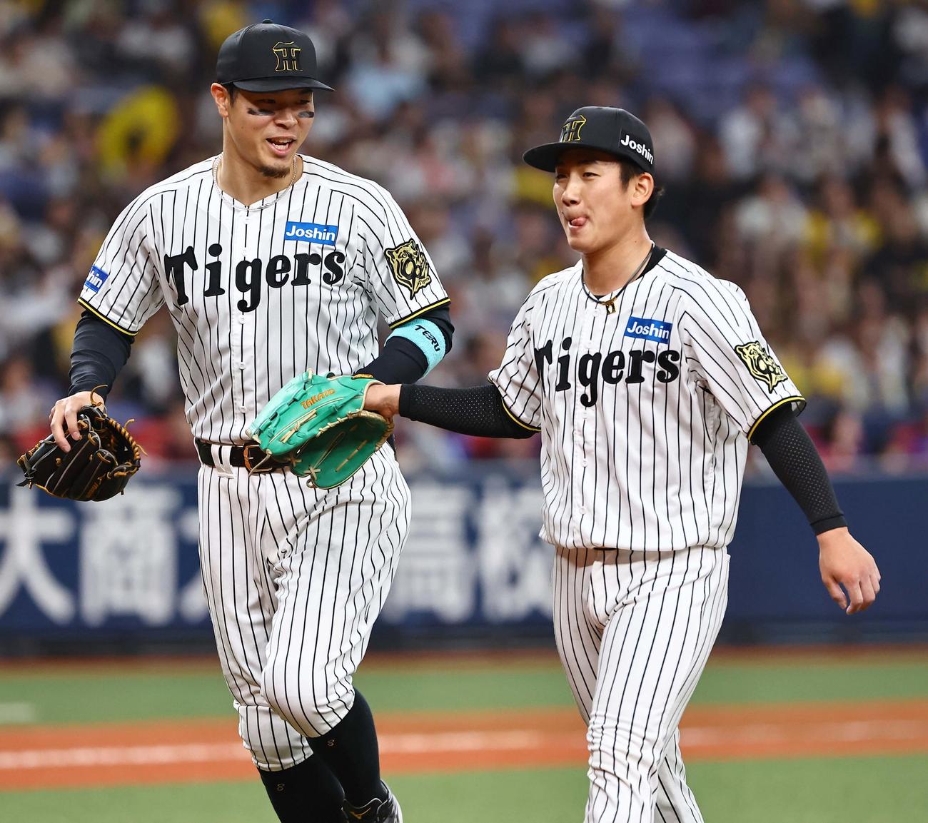 阪神対DeNA　阪神7番手の伊原（右）は11回を無失点に抑え笑顔を見せる。左はタッチを交わす佐藤輝（撮影・上田博志）