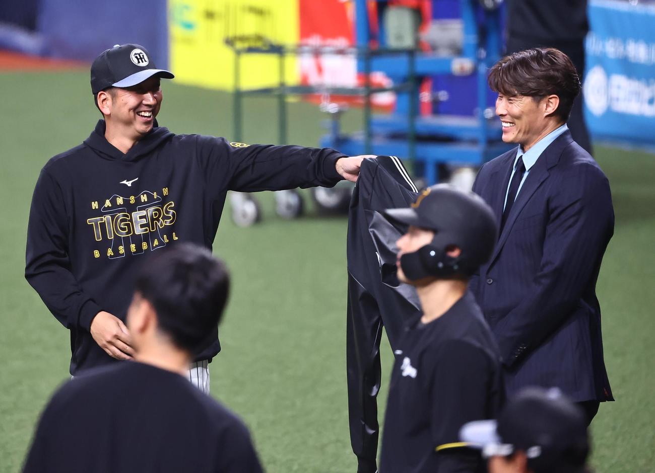 コーチの依頼？。藤川監督（左）は着ていたスタジャンを糸井氏に手渡す仕草を見せる（撮影・上田博志）