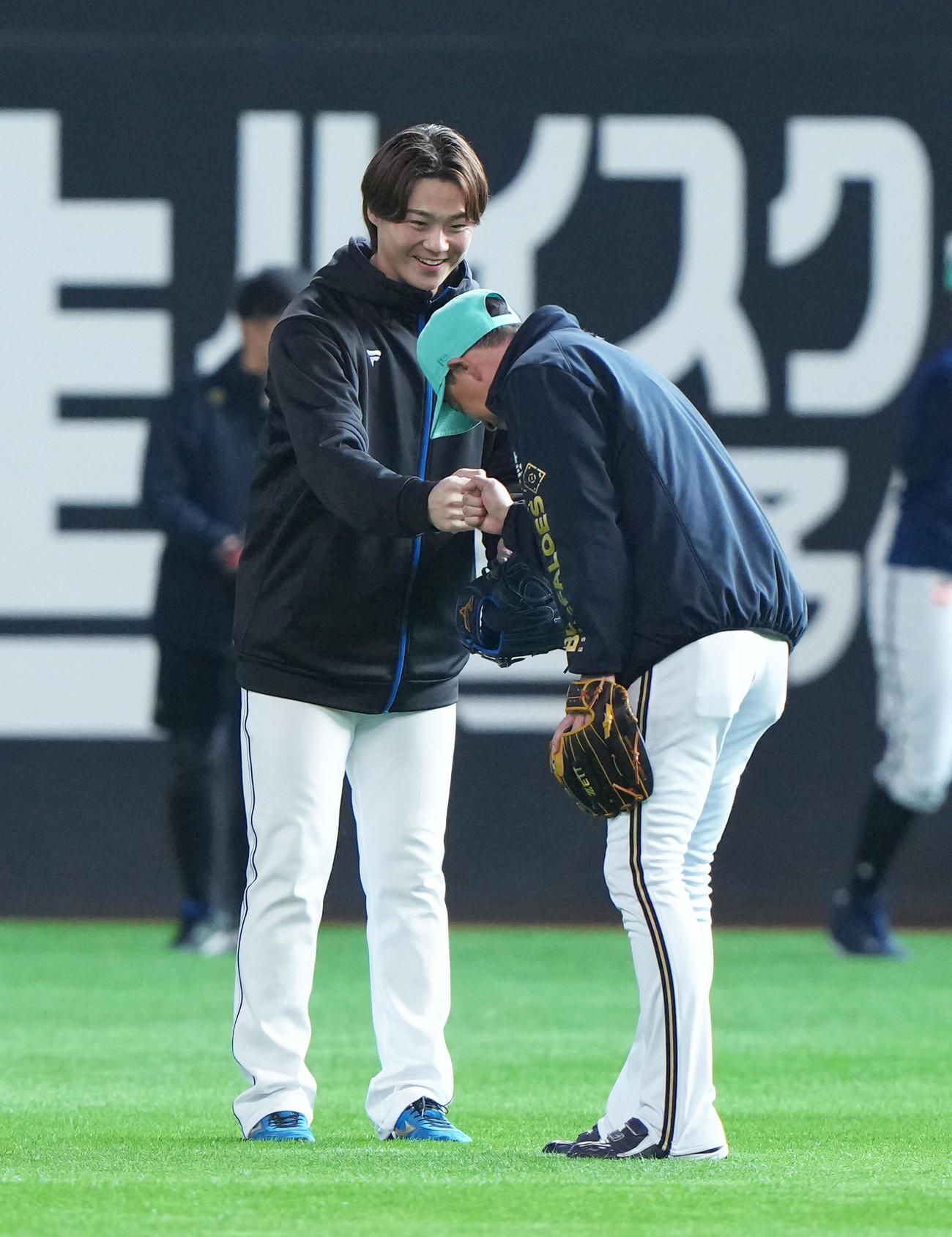 練習中、日本ハム山崎（左）とグータッチを交わすオリックス岸田監督（撮影・足立雅史）