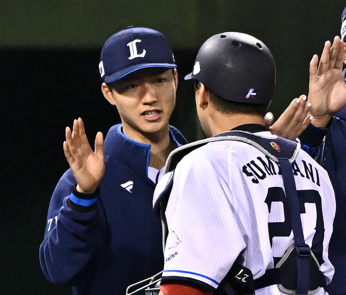 西武対ロッテ　試合後、勝利投手の西武菅井（後方）は炭谷とタッチをかわす（撮影・滝沢徹郎）