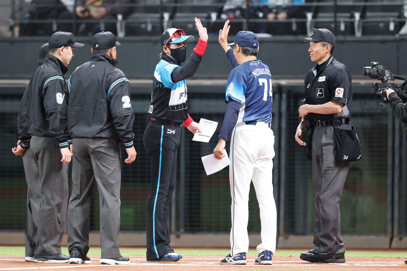 日本ハム対西武　試合前メンバー表交換で西武西口監督（中央右）とハイタッチする日本ハム新庄監督（同左）（撮影・宮地輝）