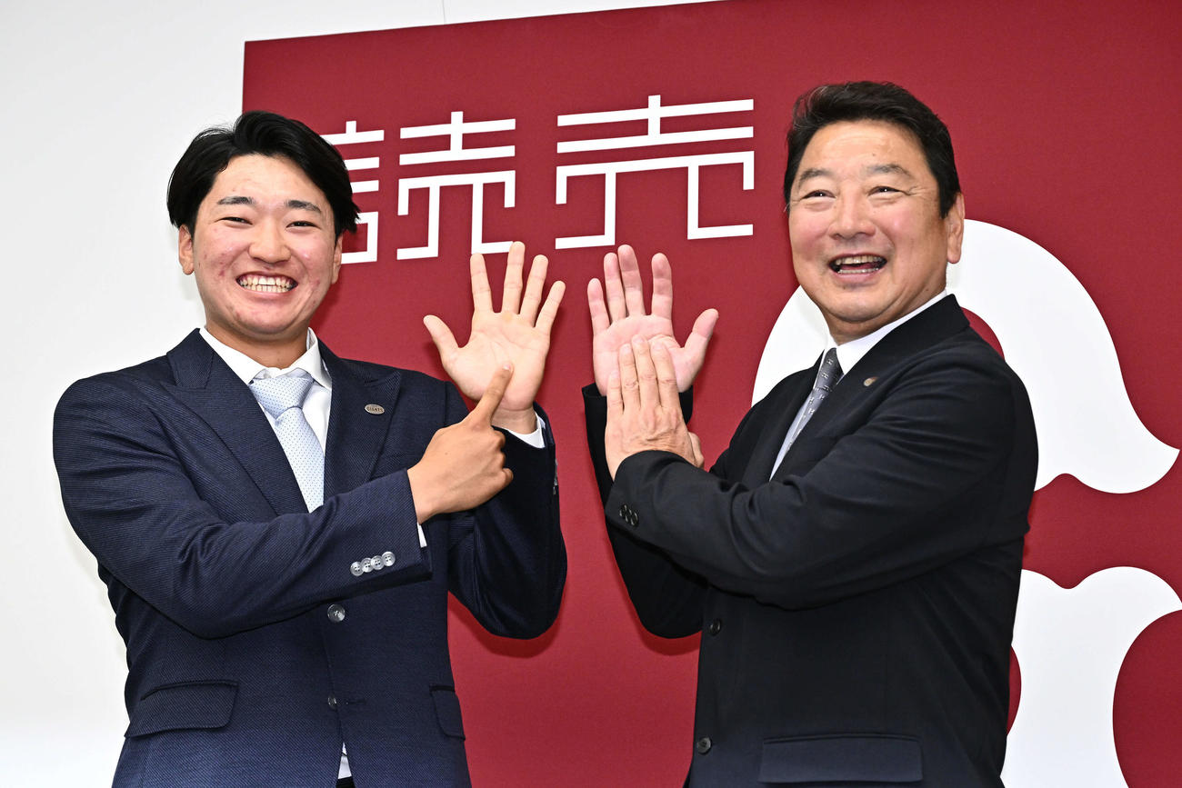 支配下に登録され新背番号の「69」を手で作る巨人笹原（左）と吉村編成本部長（撮影・滝沢徹郎）