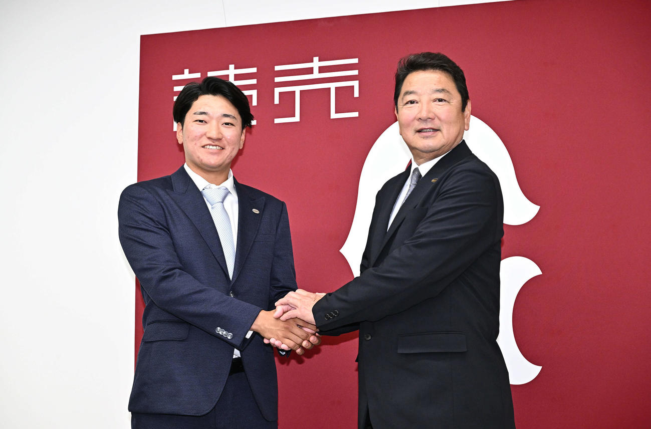 支配下に登録された巨人笹原（左）は吉村編成本部長と握手をかわす（撮影・滝沢徹郎）
