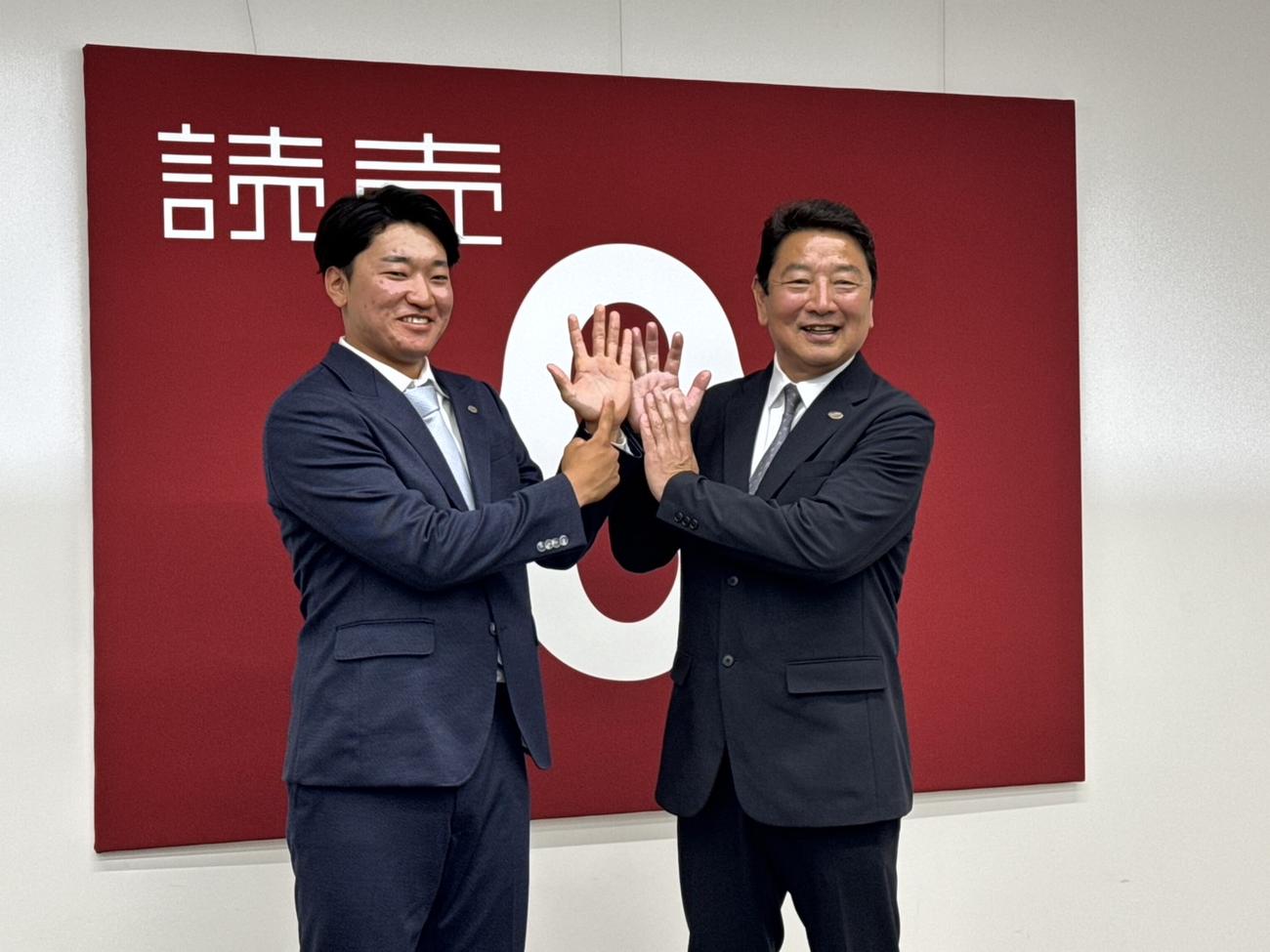 育成から支配下に昇格し会見に臨む笹原（左）は吉村編成本部長と新しい背番号にちなみ「69」をつくる