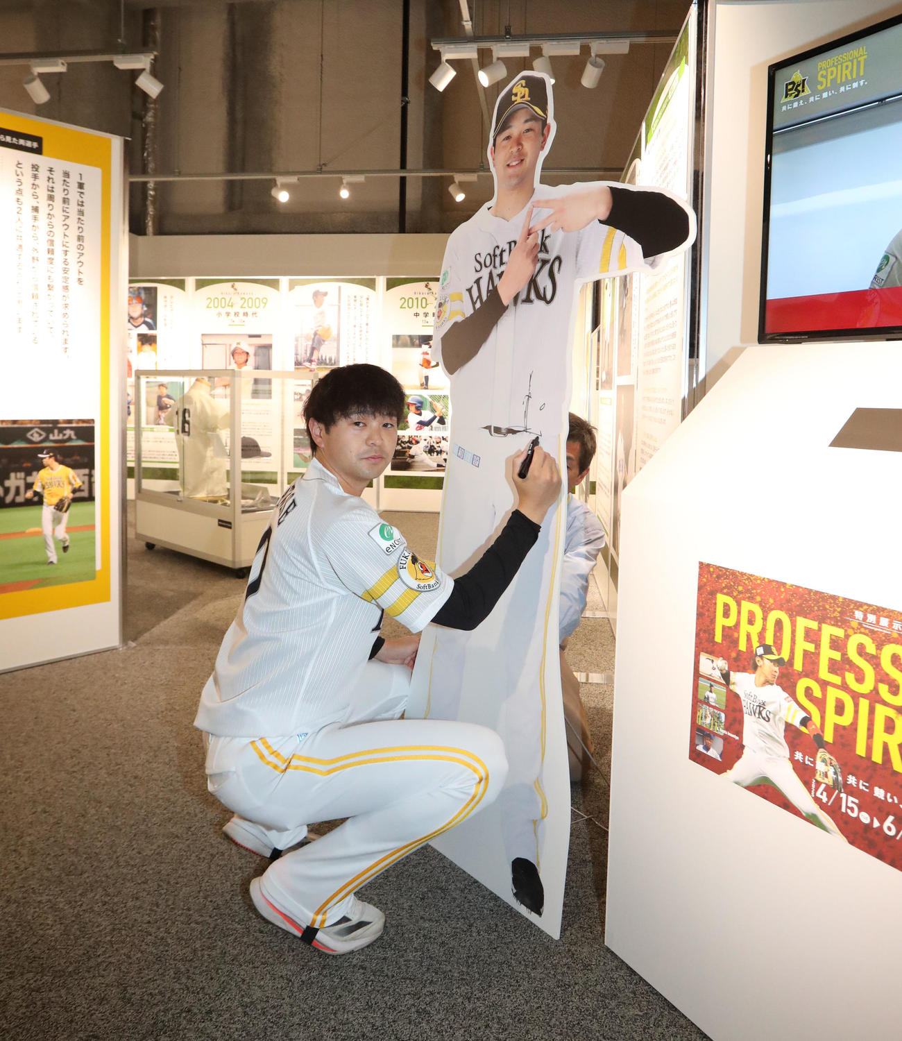 展示パネルにサインをする川瀬（撮影・梅根麻紀）