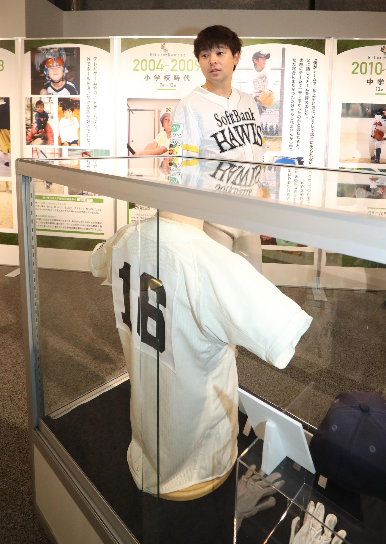 館内に展示された幼少期の写真や使用したユニホームを懐かしそうに内覧する川瀬（撮影・梅根麻紀）