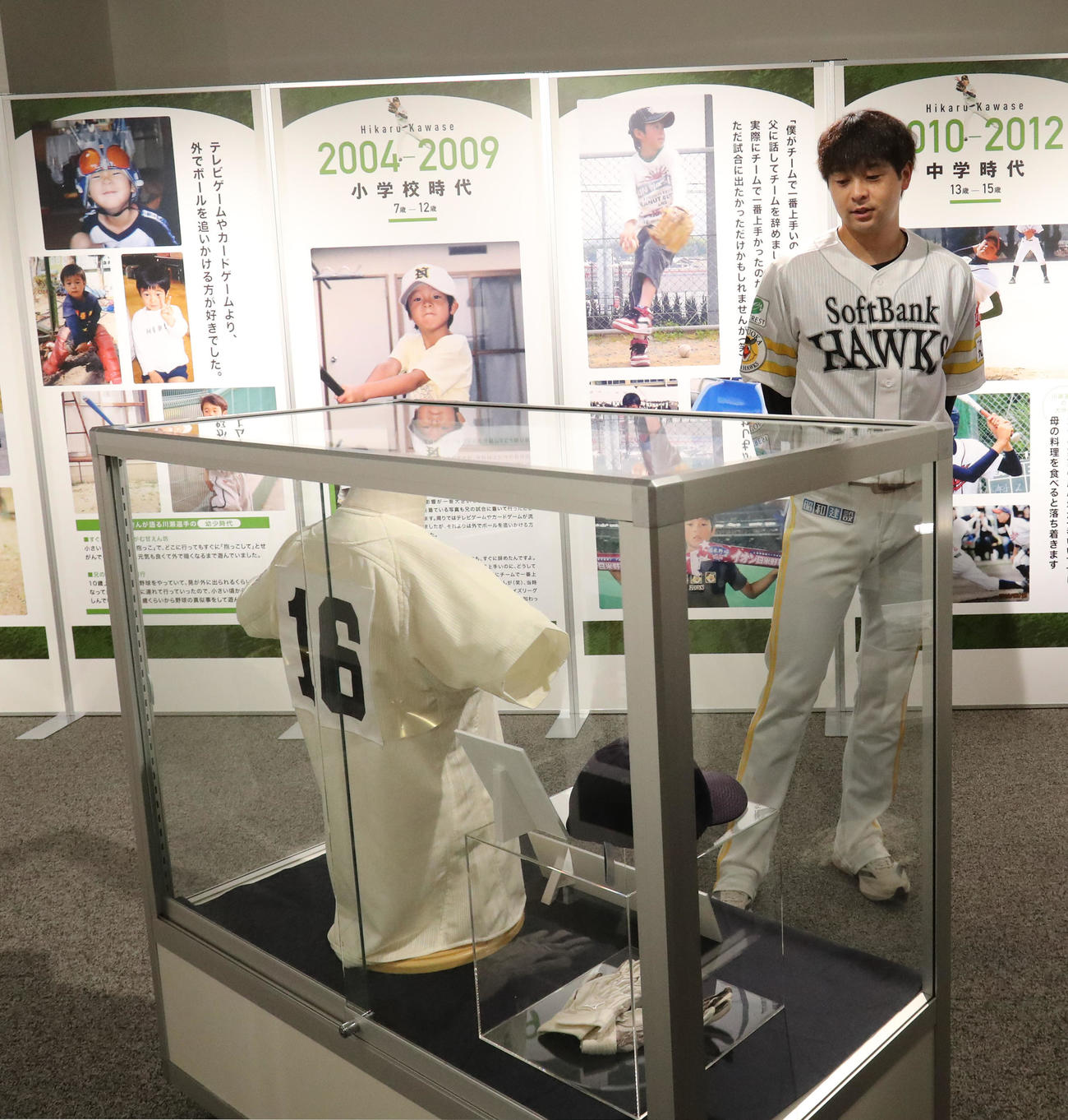 館内に展示された幼少期の写真や使用したユニホームを懐かしそうに内覧する川瀬（撮影・梅根麻紀）