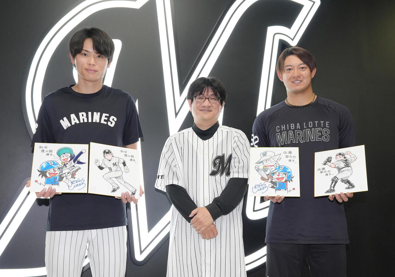 試合前、漫画「ドラベース」の作者むぎわらしんたろう氏から直筆のイラストをプレゼントされ笑顔を見せるロッテの和田（左）と佐藤（撮影・足立雅史）
