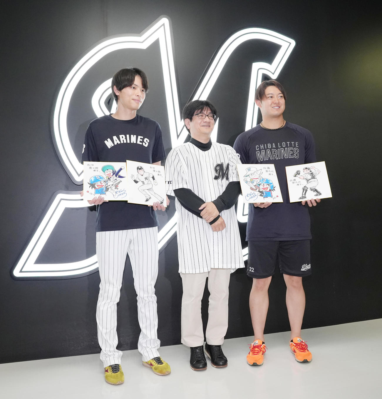 試合前、漫画「ドラベース」の作者むぎわらしんたろう氏から直筆のイラストをプレゼントされ笑顔を見せるロッテの和田（左）と佐藤（撮影・足立雅史）