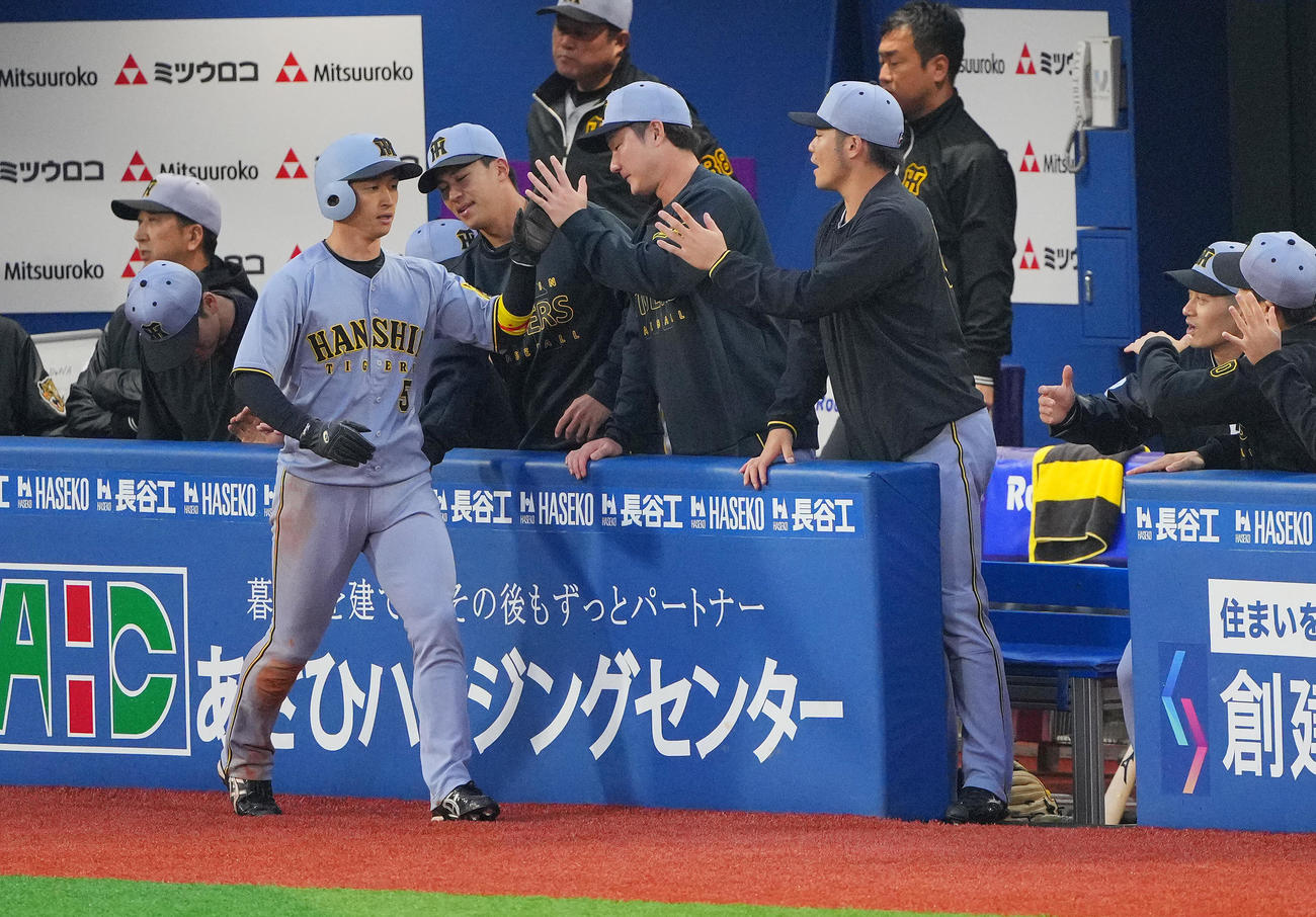 DeNA対阪神　1回表阪神1死三塁、森下の先制適時打で生還しナインの出迎えを受ける近本（左）（撮影・垰建太）
