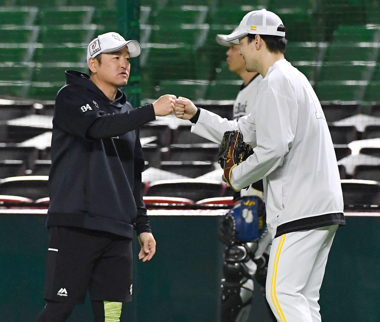 キャッチボール後の話し合いが終わり、倉野コーチ（左）とグータッチを交わす有原（撮影・岩下翔太）