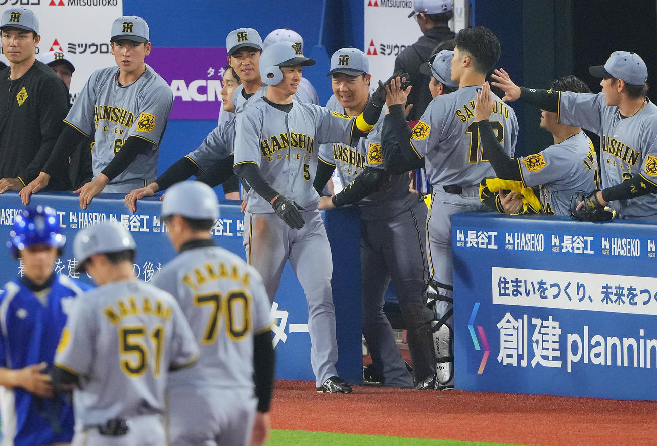 DeNA対阪神　7回表阪神2死二塁、中野の適時打で生還しナインの出迎えを受ける近本（中央）（撮影・垰建太）