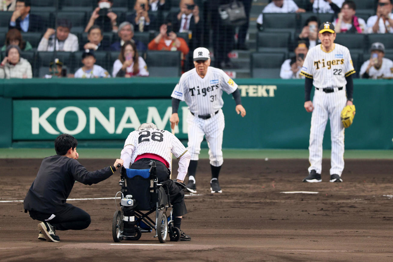 阪神対巨人阪神球団創設90周年のレジェンズデー企画でファーストピッチセレモニーを行うため車椅子から立ち上がる江夏氏。中央はびっくりしてマウンドへ向かおうとする掛布氏。右は田淵氏（撮影・加藤哉）