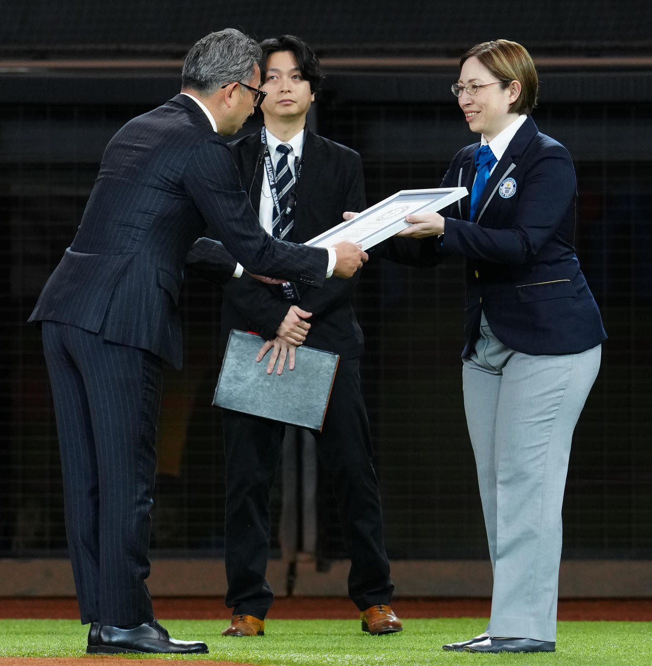 日本ハム対ロッテ　試合前、ギネス世界記録公式認定員のマクミラン舞さん（右）から認定書を受け取る前沢氏（撮影・江口和貴）