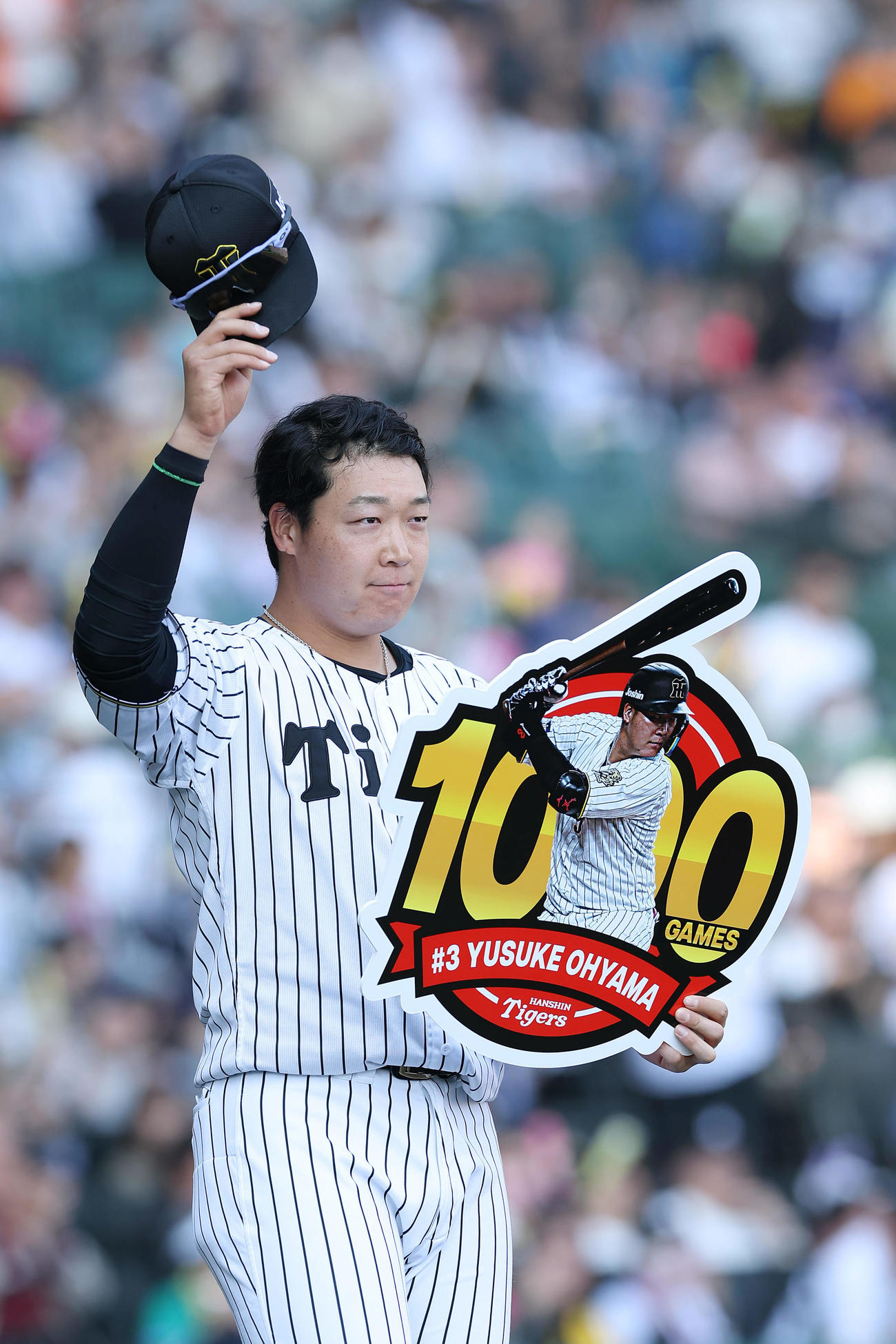 阪神対巨人　通算1000試合出場を達成し、記念ボードを手にファンの声援に応える阪神大山（撮影・前田充）