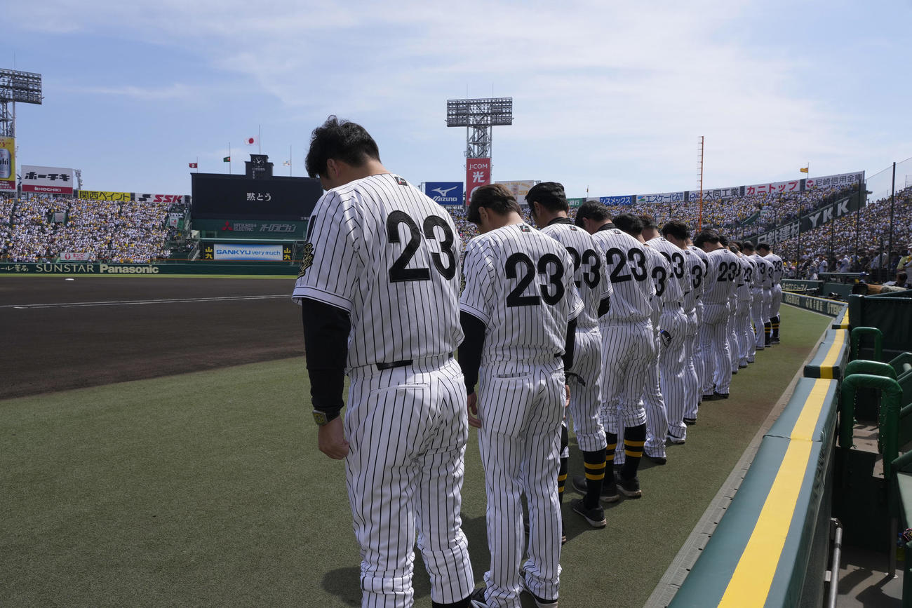 阪神対巨人　吉田義男さんの追悼試合を前に黙とうする藤川監督（手前）ら阪神の選手たち