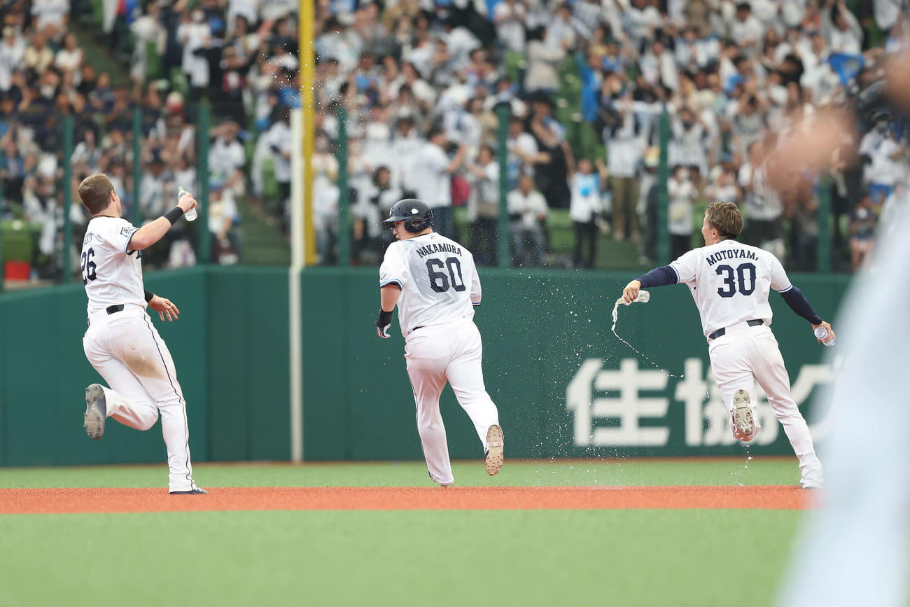 西武対オリックス　9回裏西武2死一、二塁、右前にサヨナラ適時打を放ち、チームメートの手荒い祝福から逃げる中村剛（中央）（撮影・河田真司）