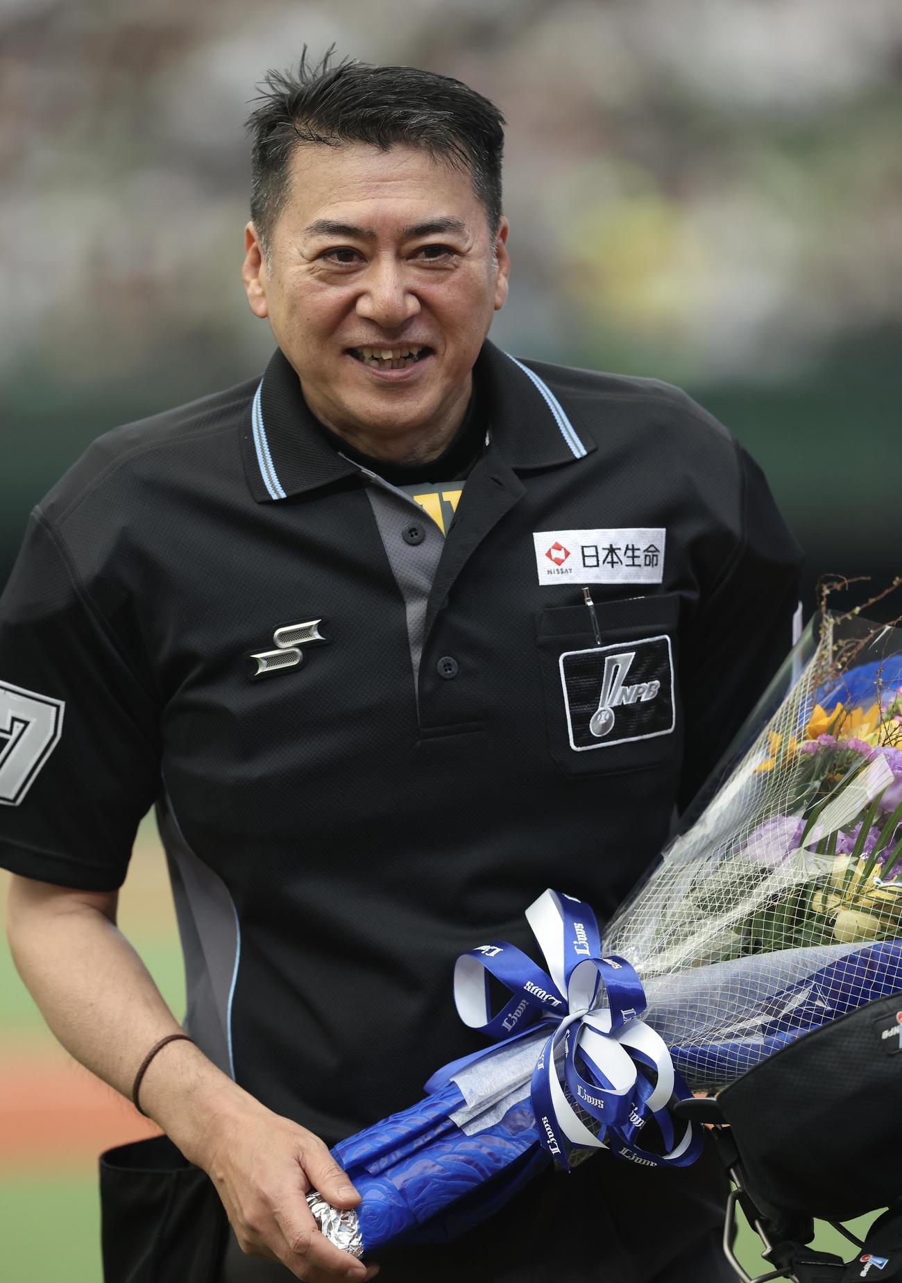 西武対オリックス　5回裏を終え、通算2500試合出場を達成し、花束を手に笑顔を見せる有隅審判員（撮影・河田真司）
