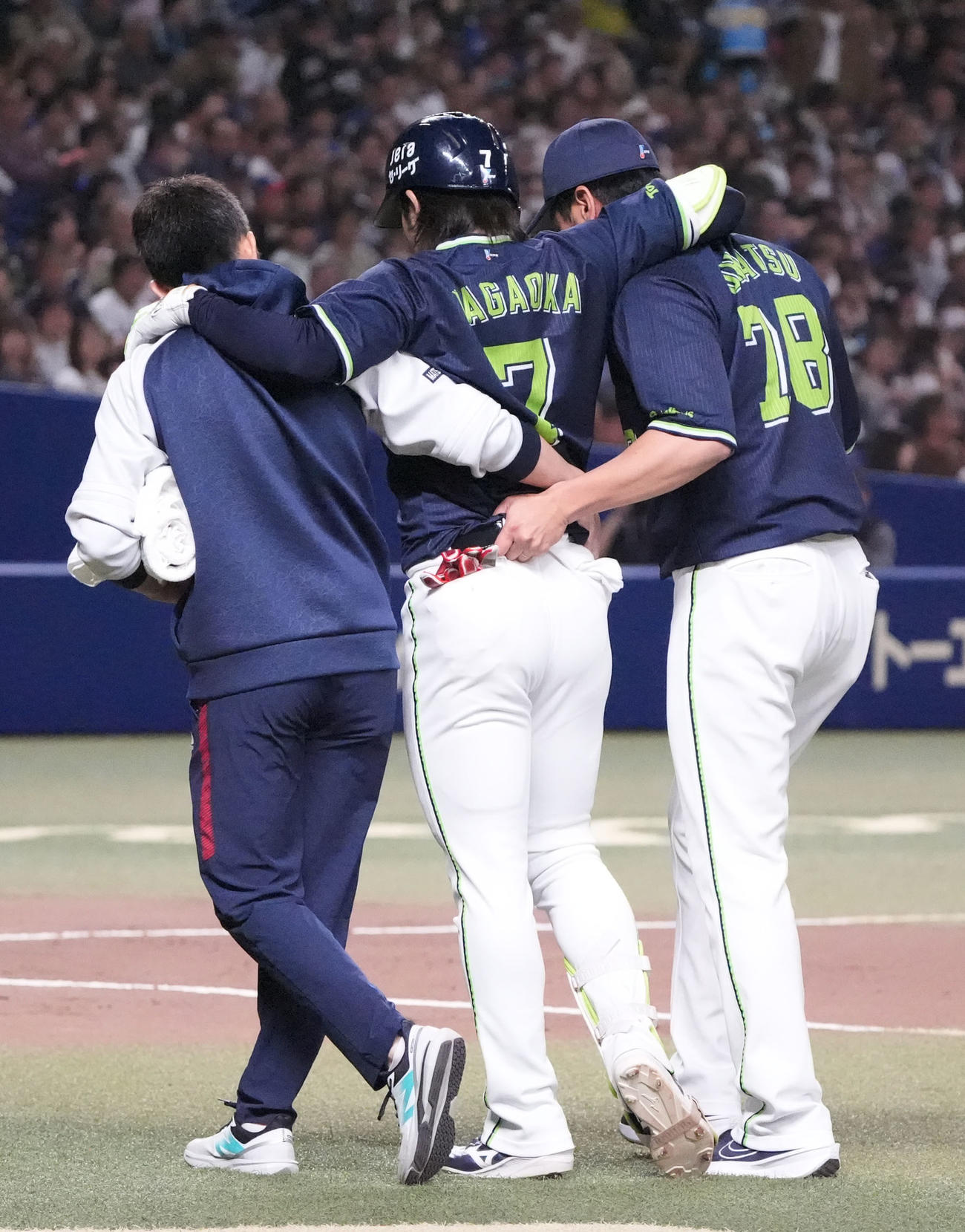 長岡（中央）は遊ゴロの際に足を痛め両脇を抱えられベンチへ戻る（2025年4月26日撮影）