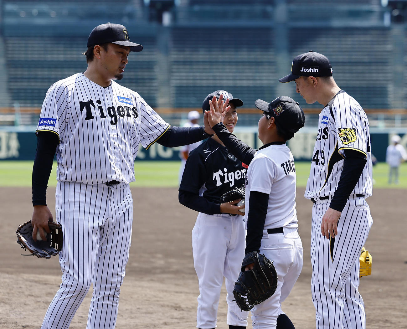 阪神OB会イベントで、子どもたちとタッチを交わす秋山拓巳（左）。右は今成亮太氏（撮影・藤尾明華）