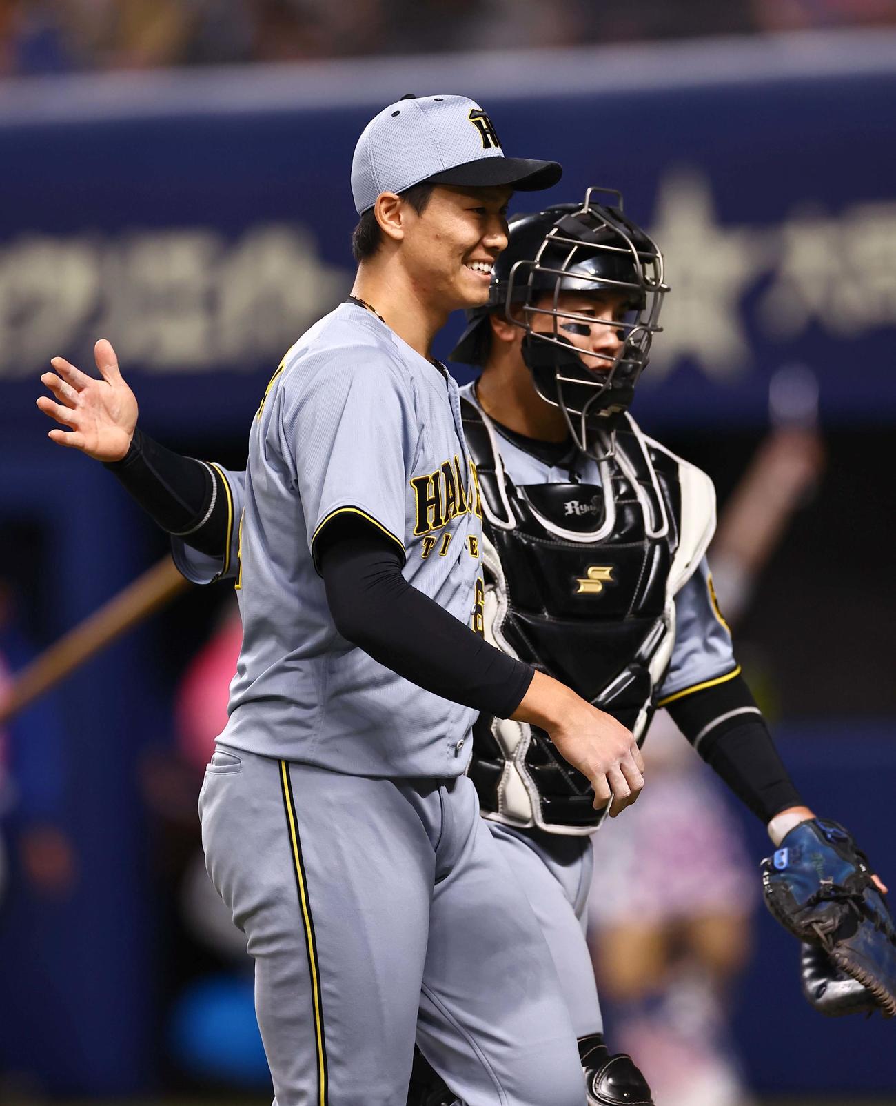 中日対阪神　8回1イニングを無失点に抑えた湯浅（左）は梅野と笑顔でベンチに引き揚げる（撮影・上田博志）