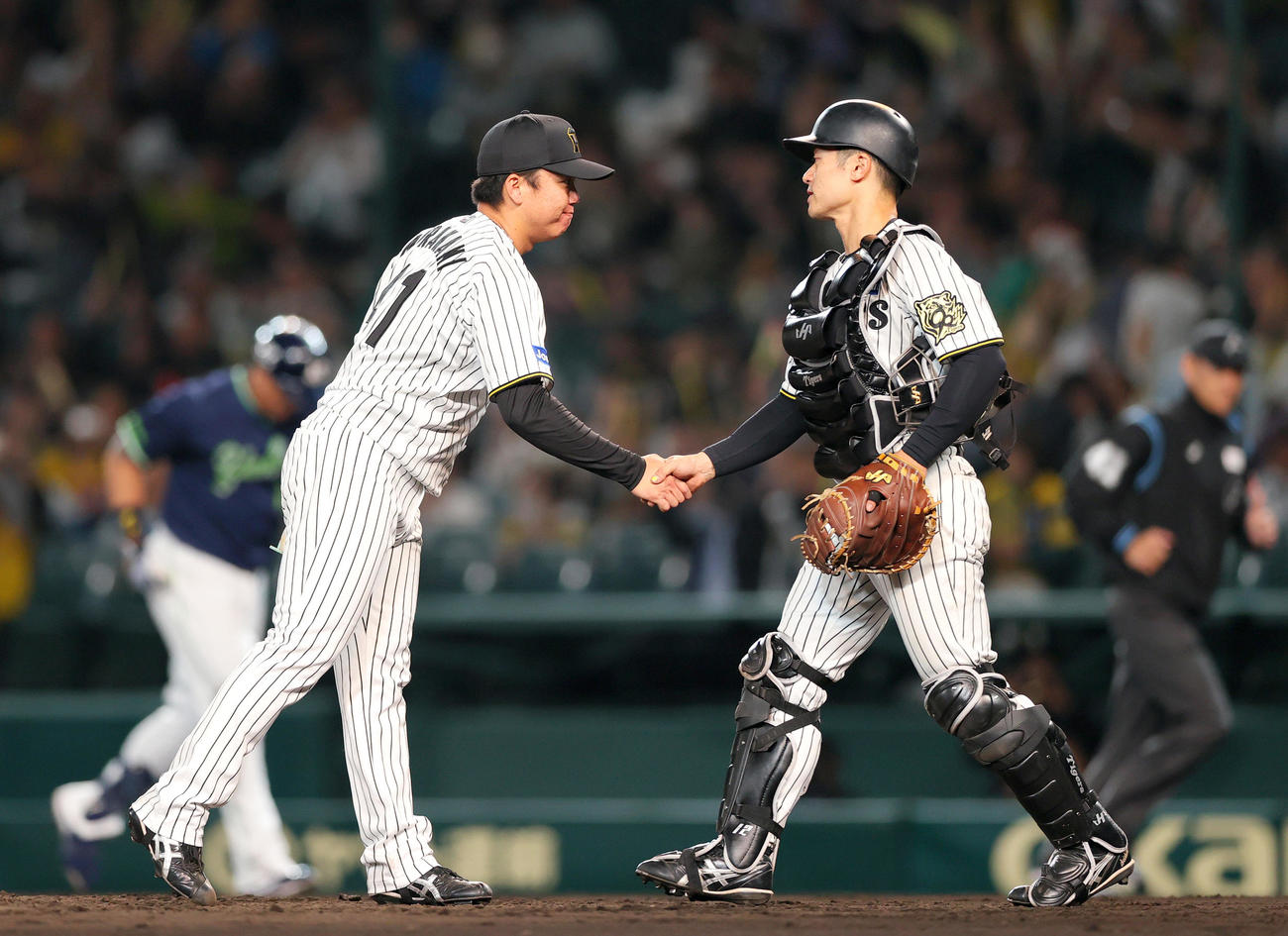 阪神対ヤクルト　ヤクルト打線を5安打完封した村上（左）は捕手坂本と握手をかわす（撮影・上山淳一）