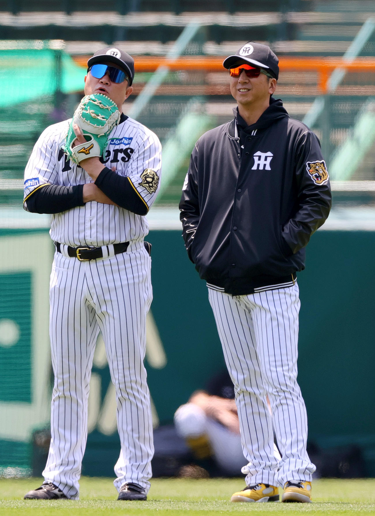 阪神対ヤクルト　試合前の練習で、阪神藤川監督（右）は安藤投手チーフコーチとリラックスした表情で話す（撮影・上山淳一）