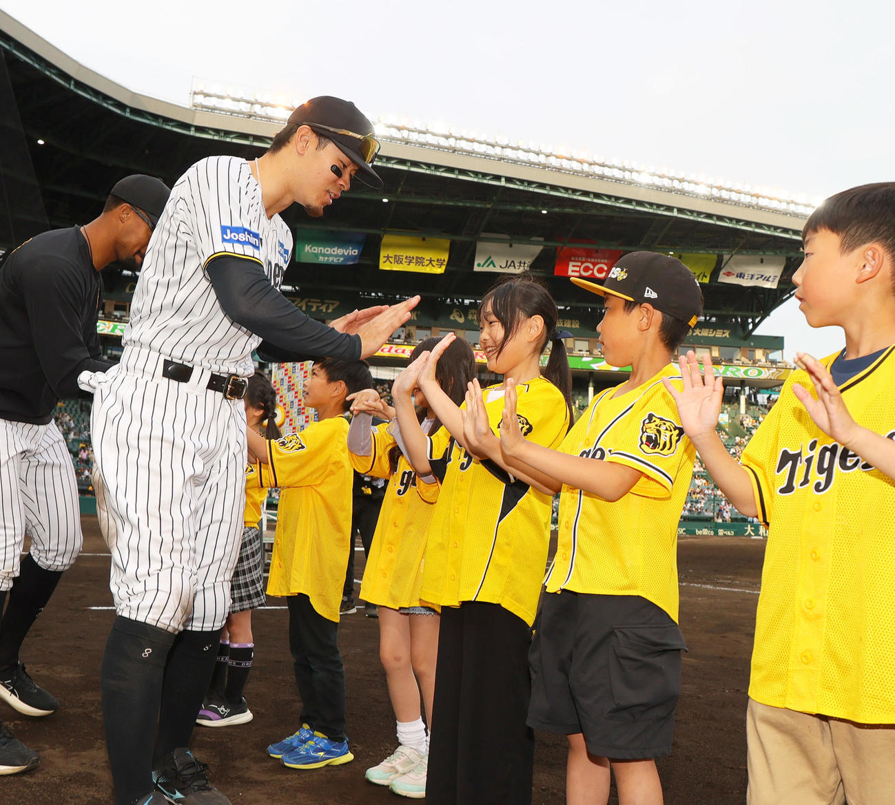 阪神対ヤクルト　ヤクルトに勝利し、ヒーローの佐藤輝は児童とタッチをかわす（撮影・上山淳一）