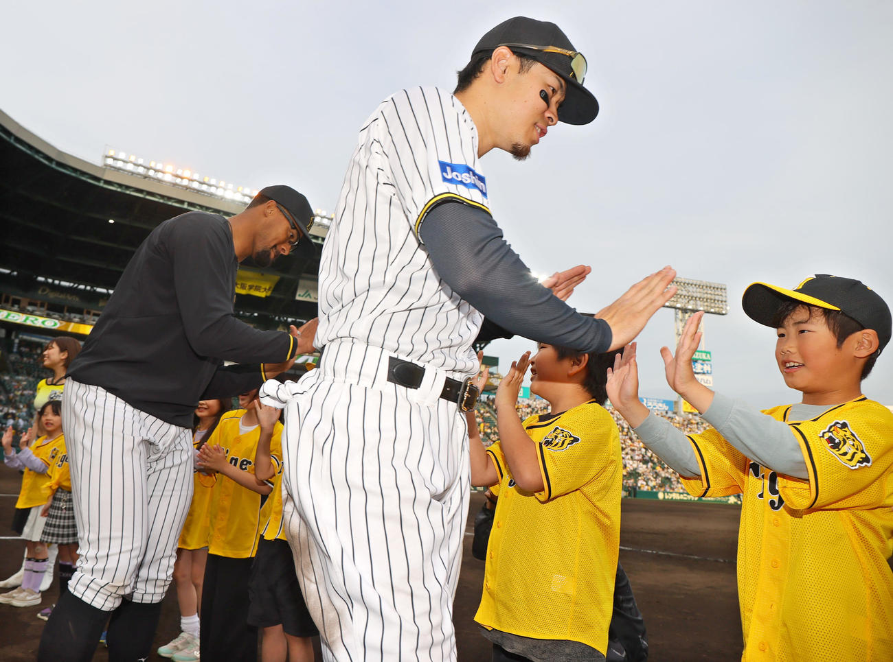 阪神対ヤクルト　ヤクルトに勝利し、ヒーローの佐藤輝（中央）とデュプランティエは児童とタッチをかわす（撮影・上山淳一）