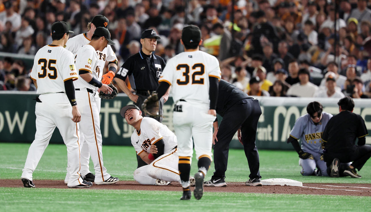 巨人対阪神　1回表阪神無死一塁、岡本は中野（右）の三塁犠打で浦田からのボールを捕球しタッチに行った際接触、倒れ込んで苦しみの表情を見せる（撮影・加藤哉）