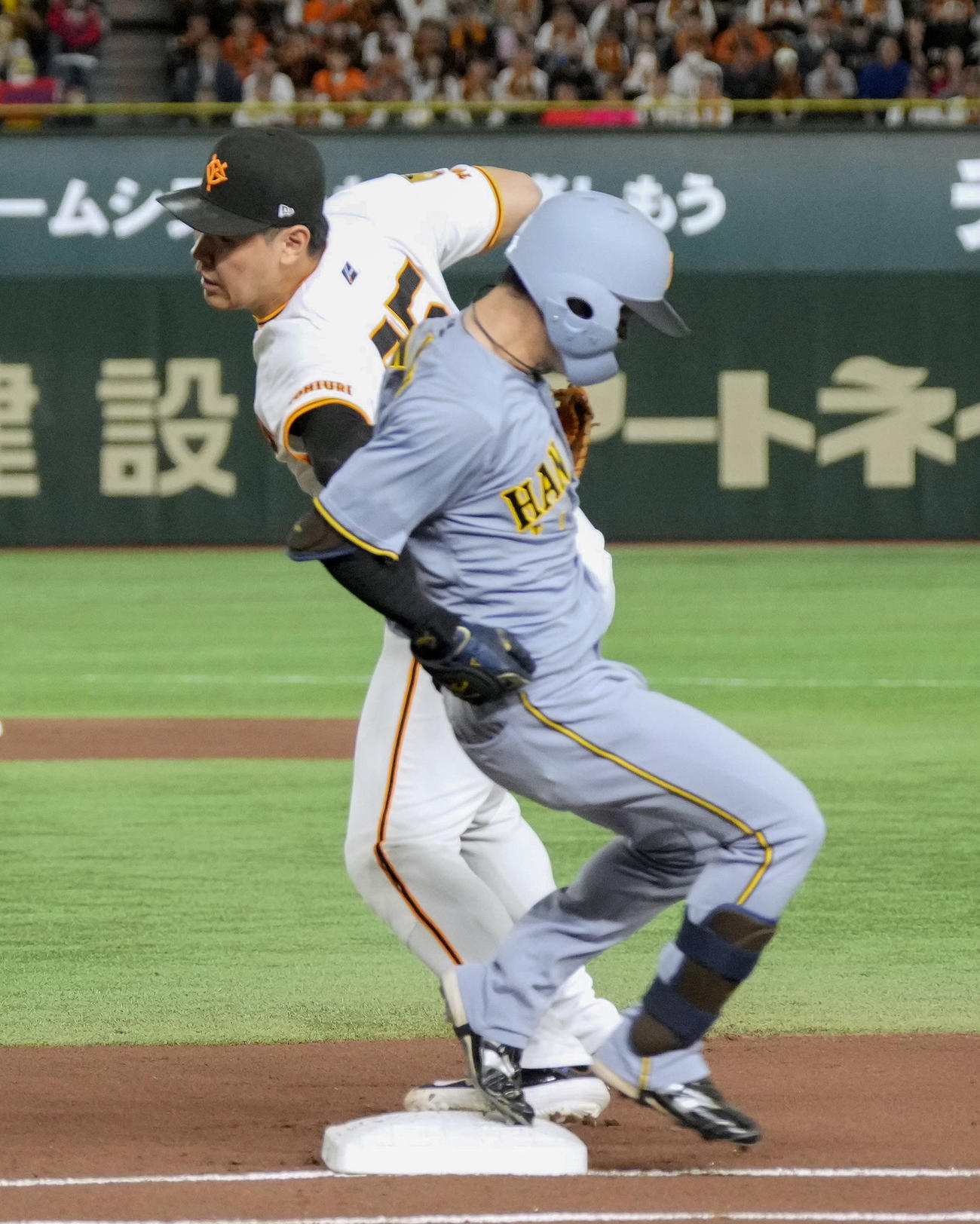 1回阪神無死一塁、中野（右）と塁上で交錯する巨人の一塁手岡本（共同）