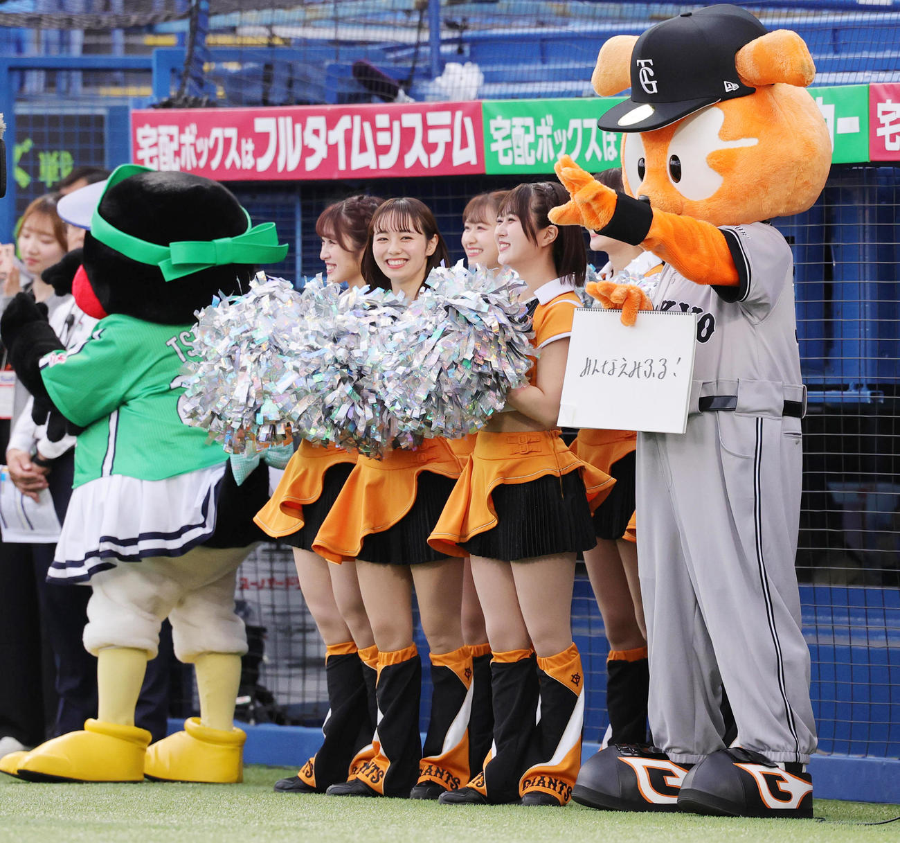 ヤクルト対巨人　試合前に登場したジャビッ（右端）は、つば九郎が愛した言葉「みんなえみふる！」と記したフリップを出す。左端はつばみ（撮影・野上伸悟）