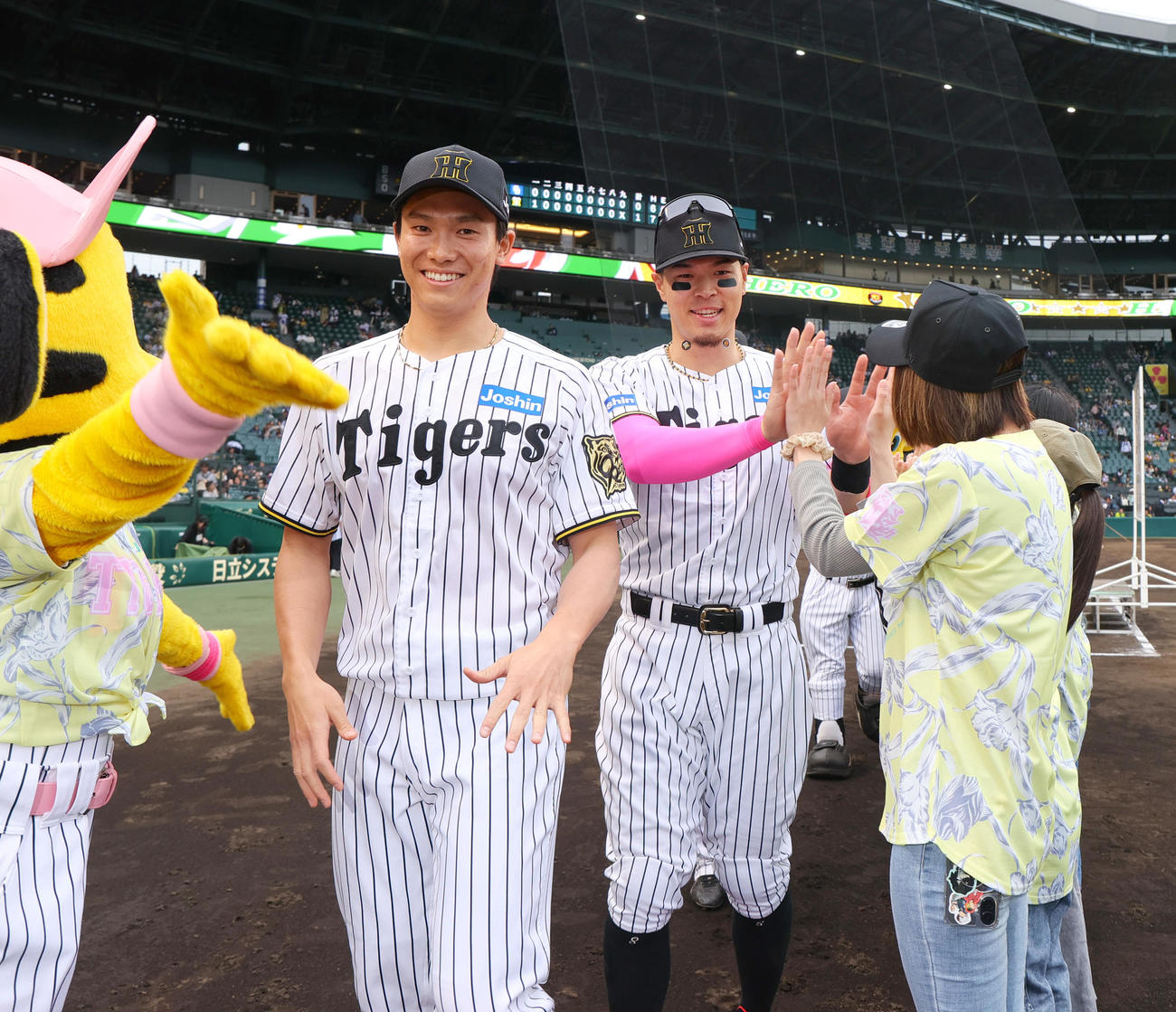 阪神対中日　TORACOユニホームを着たファンとタッチをかわす湯浅（左）と佐藤輝（撮影・上山淳一）