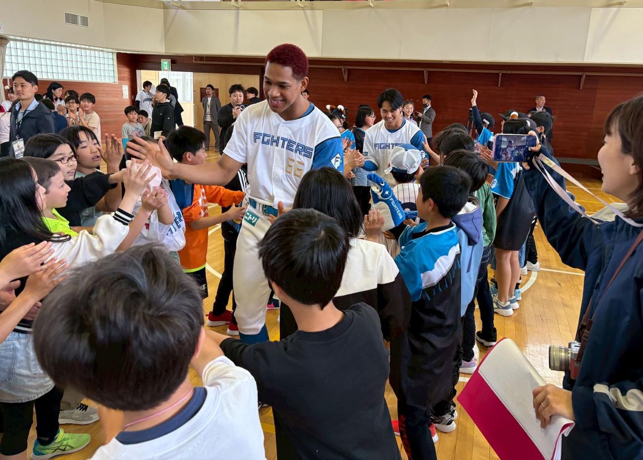 北広島双葉小を児童とハイタッチしながら会場を出る日本ハムの（左から）万波、細川（撮影・永野高輔）