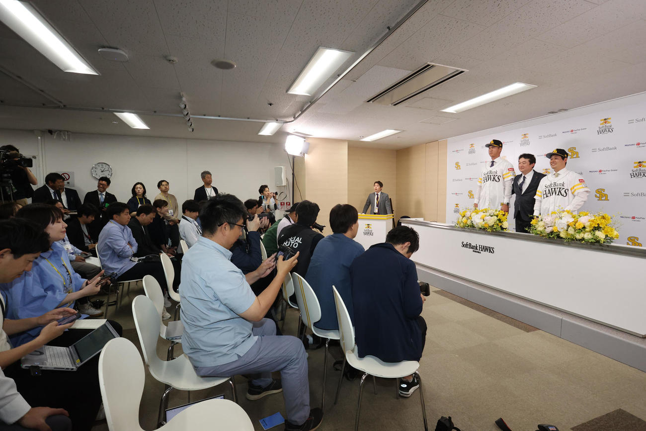 入団会見でユニホーム姿を披露する秋広（左）と大江、中央は三笠GM（撮影・梅根麻紀）