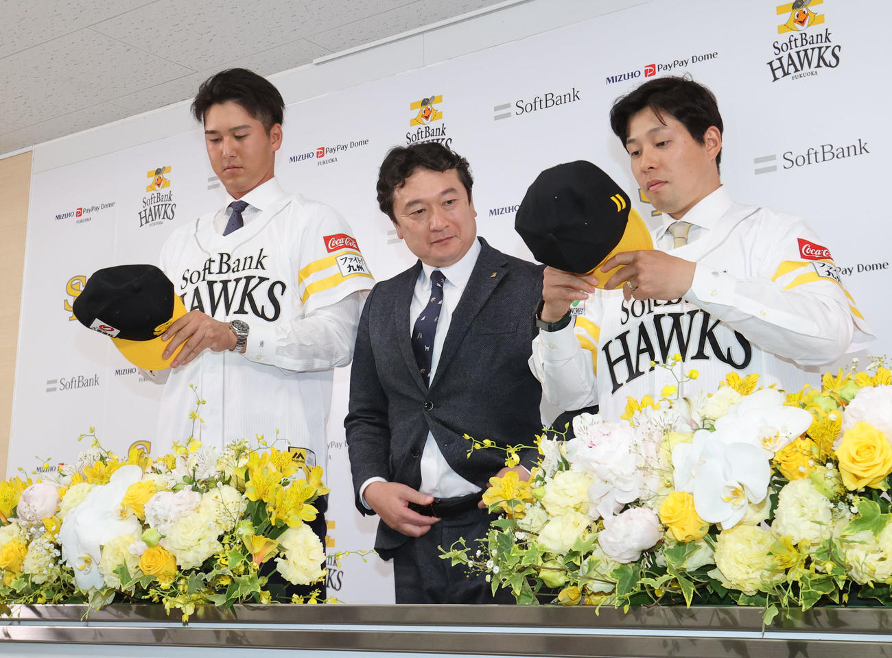 入団会見でユニホーム姿を披露する秋広（左）と大江、中央は三笠GM（撮影・梅根麻紀）