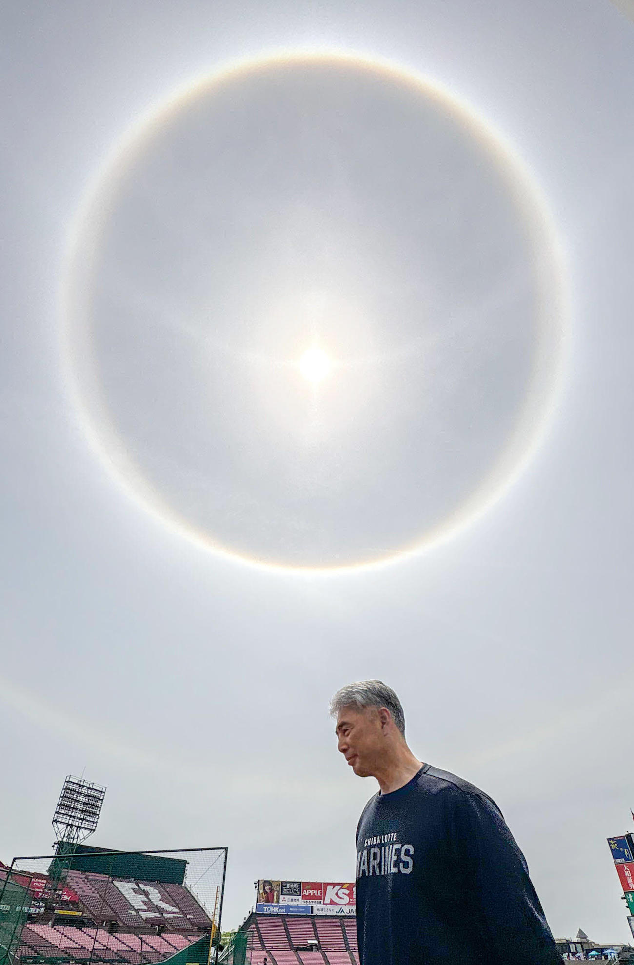 楽天対ロッテ　試合前、楽天モバイルパーク上空では太陽の周りに虹のような光の輪ができる「日暈（ひがさ）」とも言われるハロ現象が見られた。手前はロッテ吉井監督（撮影・江口和貴）