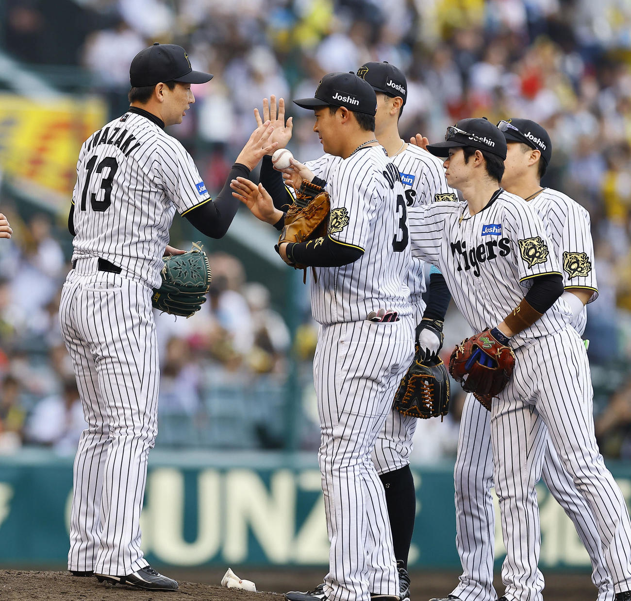 阪神対広島　通算100セーブを上げ、中野からウイニングボールを受け取る阪神岩崎（左端）崎（撮影・藤尾明華）