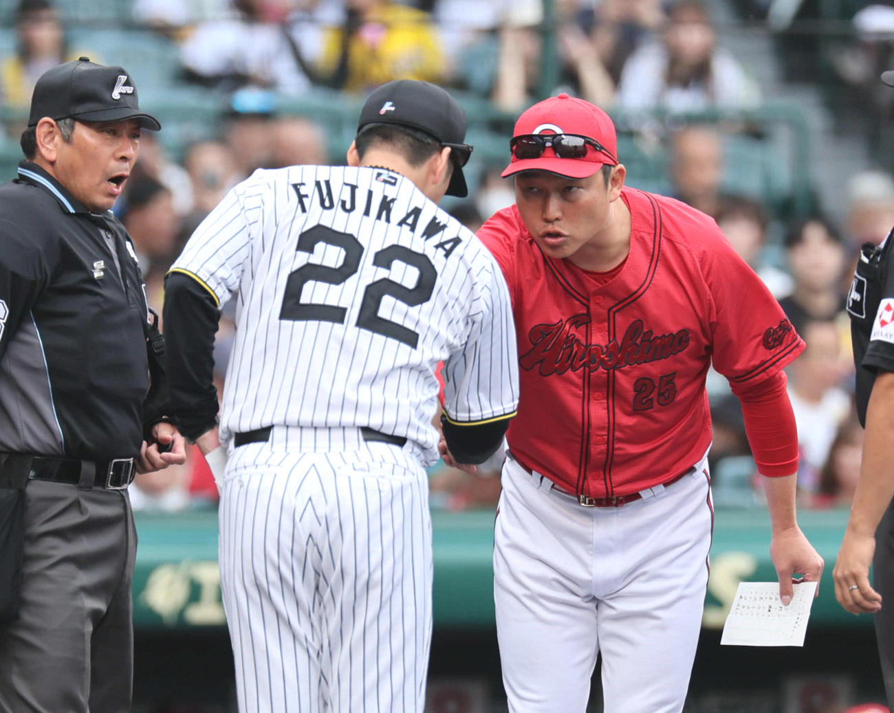 阪神対広島　メンバー確認で目を合わせ、あいさつと握手を交わした阪神藤川監督（左）と広島新井監督（撮影・宮崎幸一）