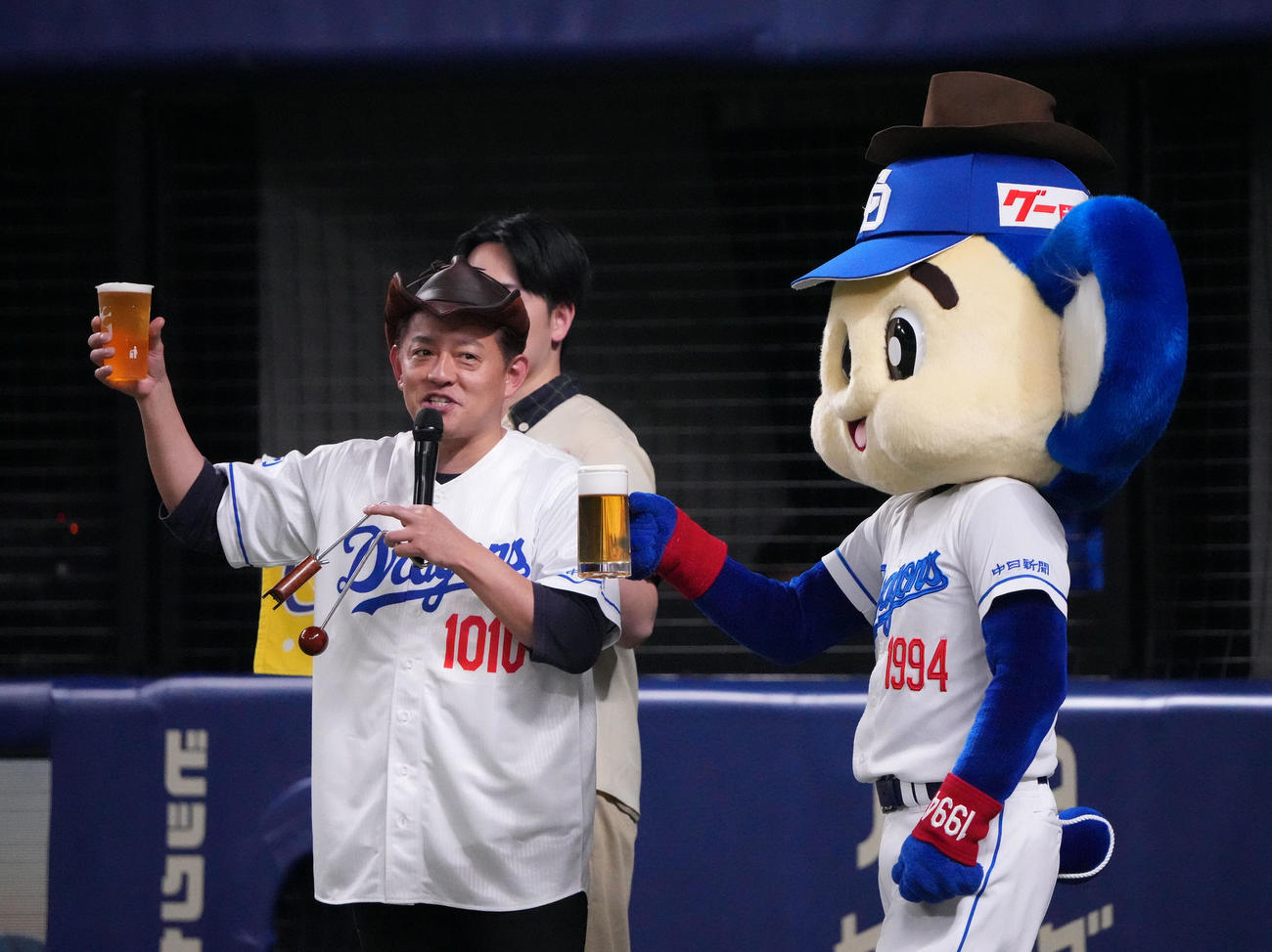 中日対ヤクルト　2回表終了、ビールを片手にファンとカンパイするカンパイ師匠（左）。右はドアラ（撮影・森本幸一）