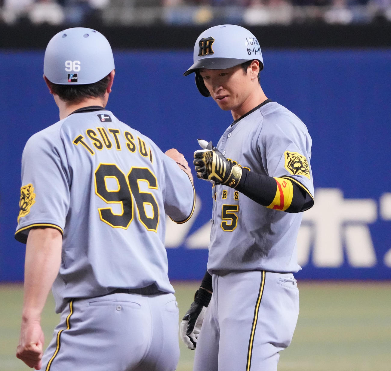 中日対阪神　11回表阪神1死二塁、近本（右）は中前適打を放ち筒井外野守備兼走塁コーチとタッチを交わす（撮影・森本幸一）