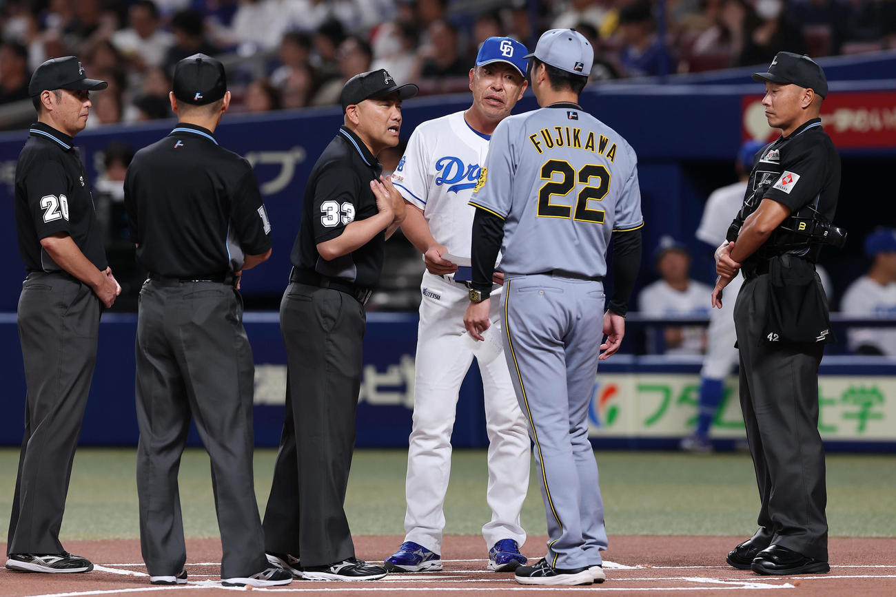 中日対阪神　試合前、メンバー表の交換で審判団から説明を受ける中日井上監督（右3人目）と阪神藤川監督（同2人目）（撮影・前田充）