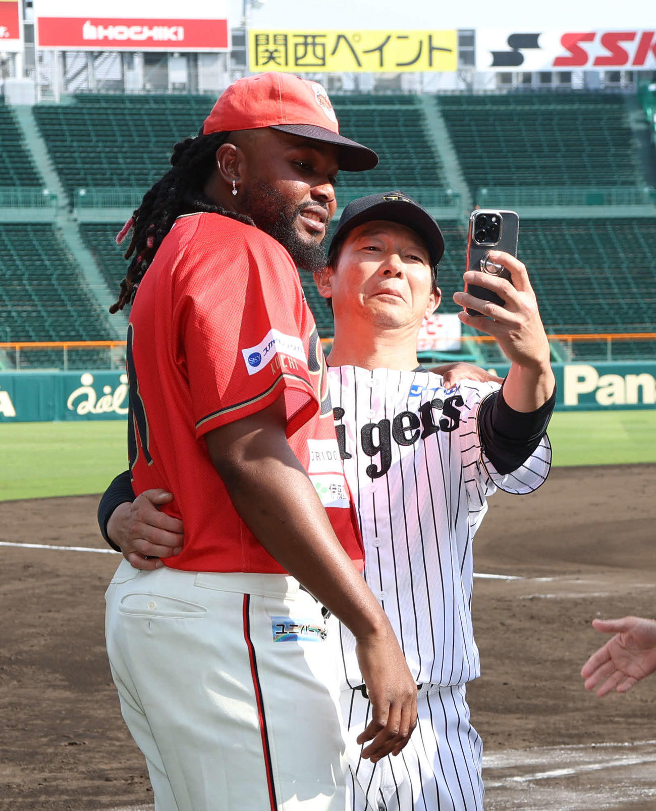 阪神対独立L連合　甲子園のマウンドに上がった阪神の元守護神、高知ドリス（左）は試合後、阪神鈴衛ブルペン捕手と旧交を温め記念写真に納まる（撮影・西尾就之）