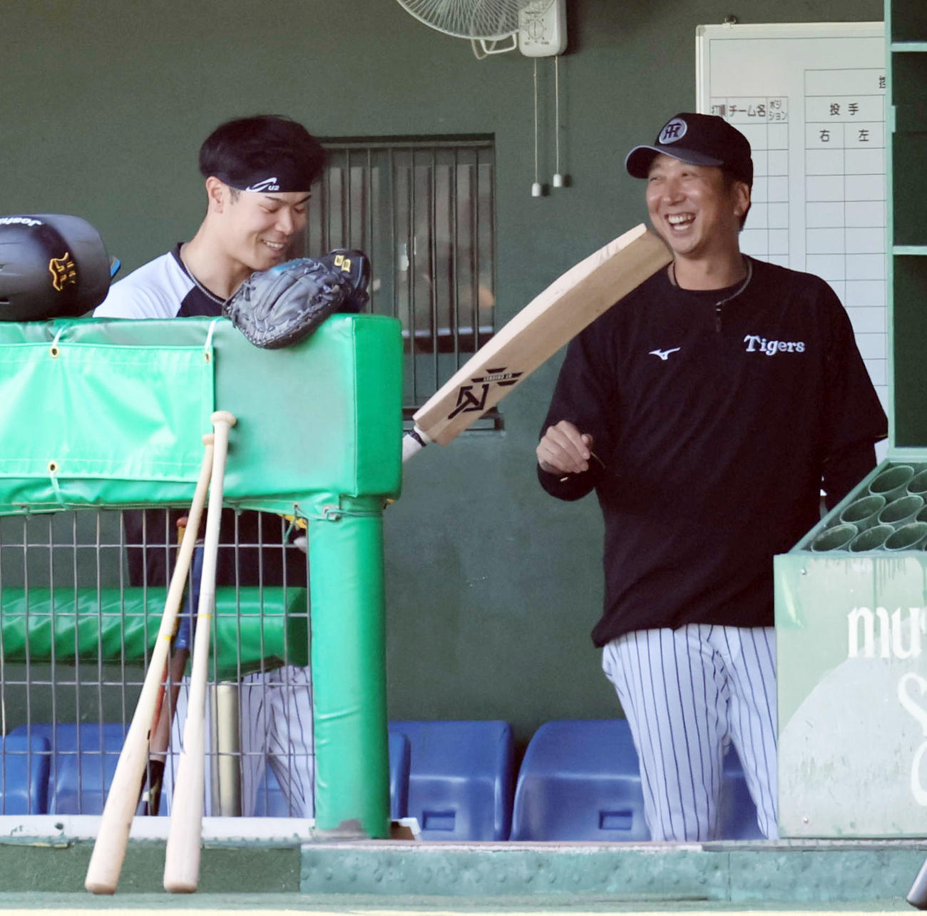 阪神対DeNA　ベンチでクリケットバットを手に談笑する佐藤輝（左）と藤川監督（撮影・宮崎幸一）